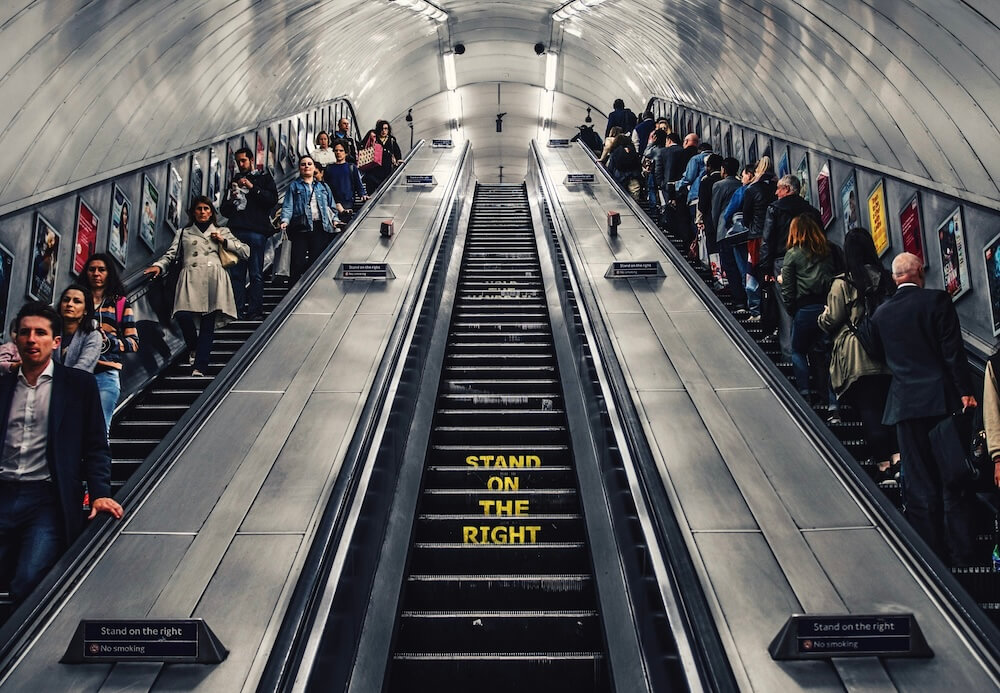 Menschen auf einer Rolltreppe, mittig der Hinweis: Stand on the right.