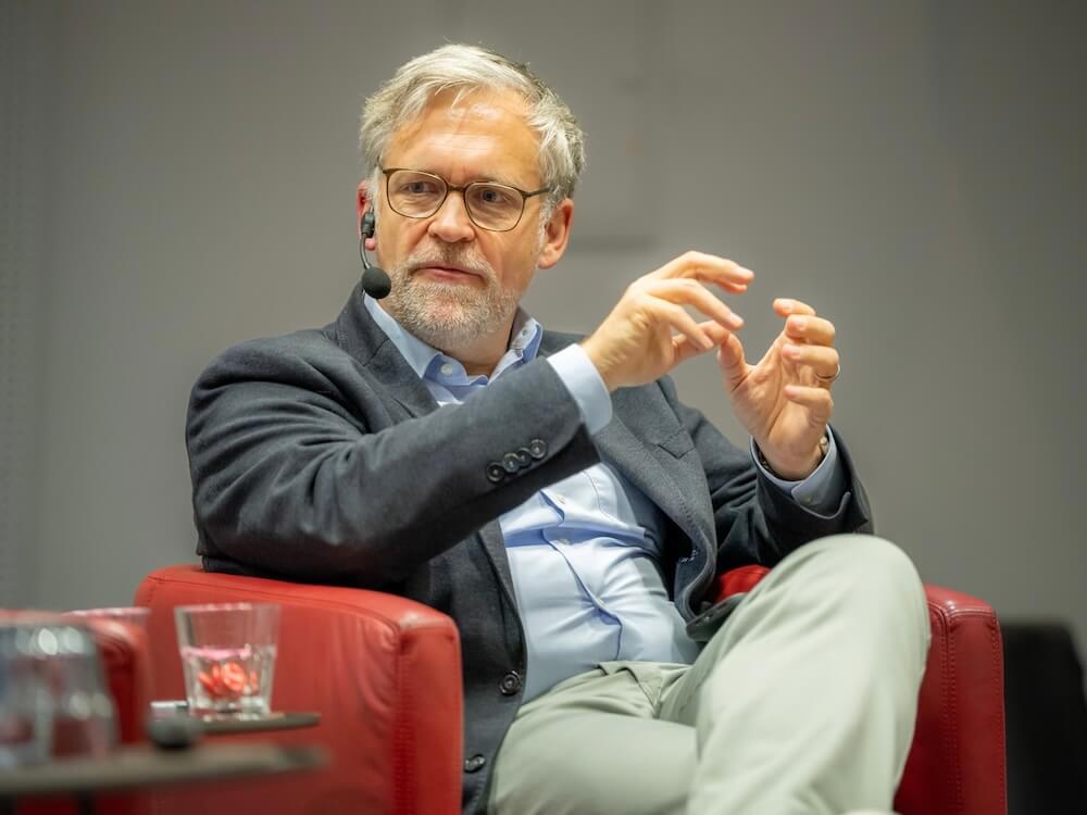 Thorsten Kausch sitzt mit Mikrofon in einer Talkrunde zu Stadtvermarktung und Stadtentwicklung